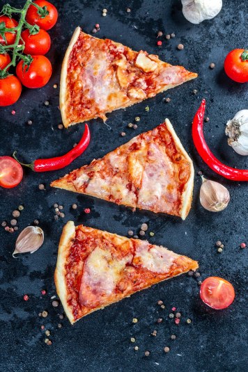 Flat lay composition slices of pizza with bacon, cheese and toma